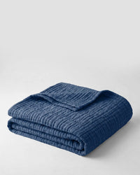 Muslin Blanket in Blue draped over a bed