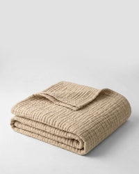 Muslin Blanket in Dune draped over a bed