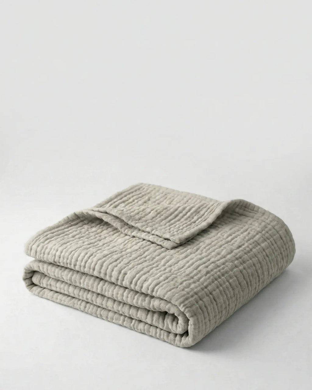 Muslin Blanket in Grey draped over a bed