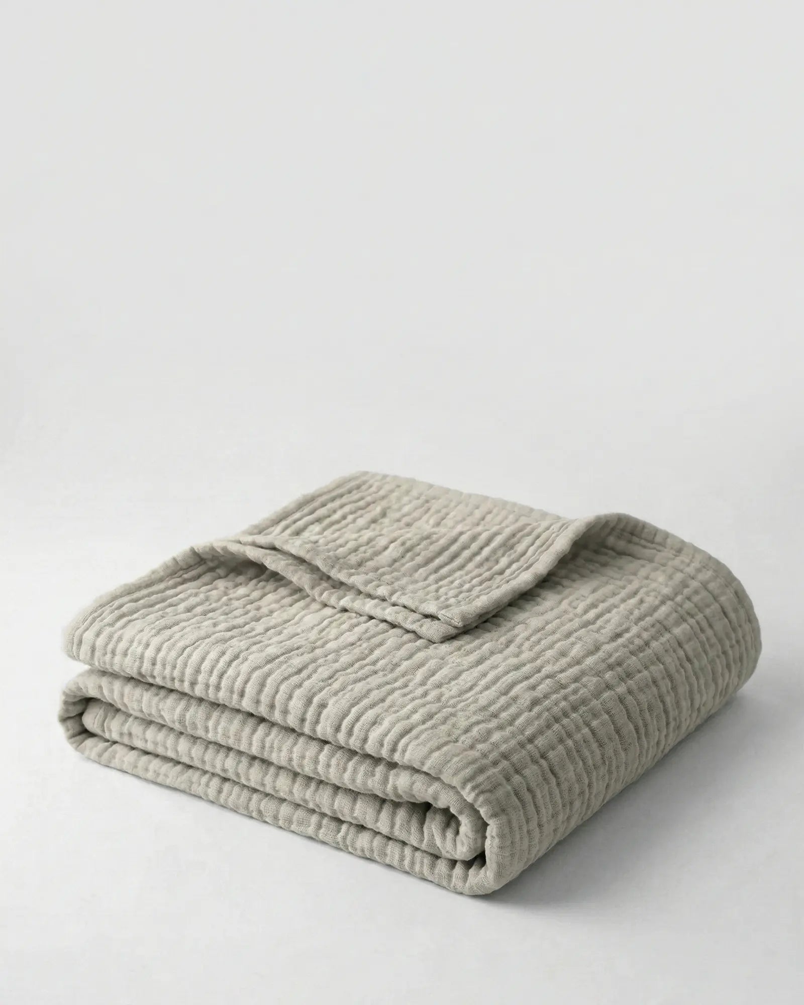 Muslin Blanket in Grey draped over a bed