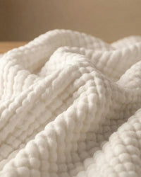 Muslin Blanket in White in a bedroom