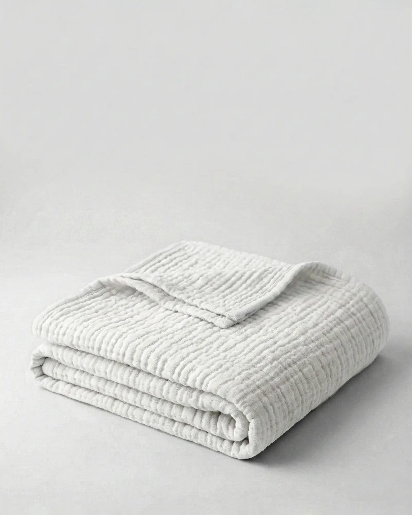 Muslin Blanket in White draped over a bed